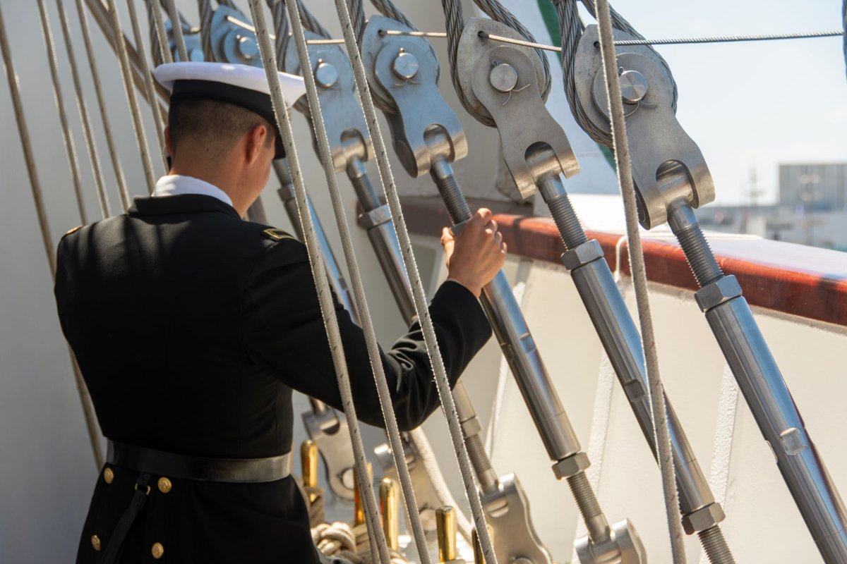 Marinheiro ajustando cordas no convés de um navio