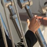 Marinheiro ajustando cordas no convés de um navio