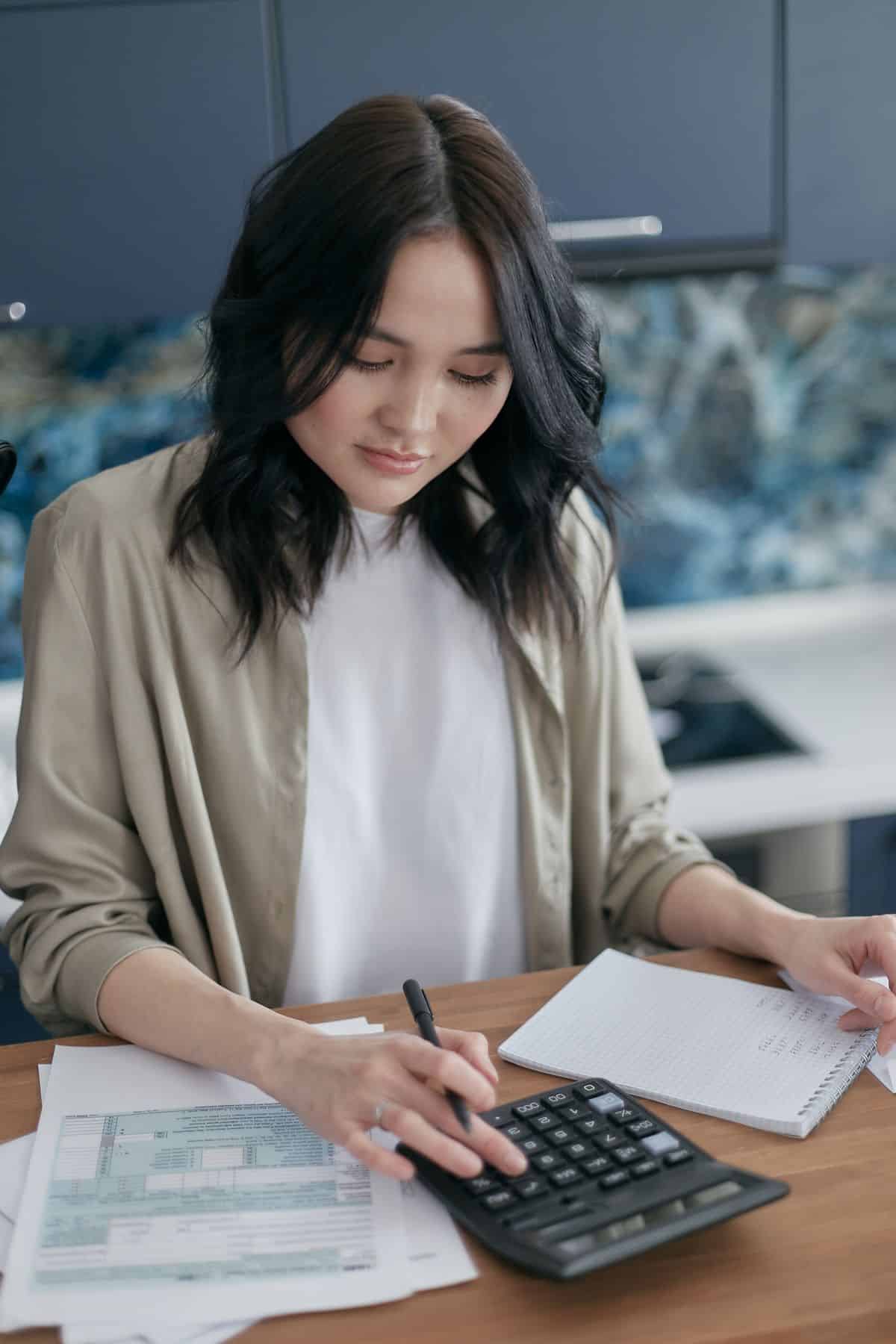 Mulher organizando as contas com uma calculadora, ilustrando a contribuição ao INSS